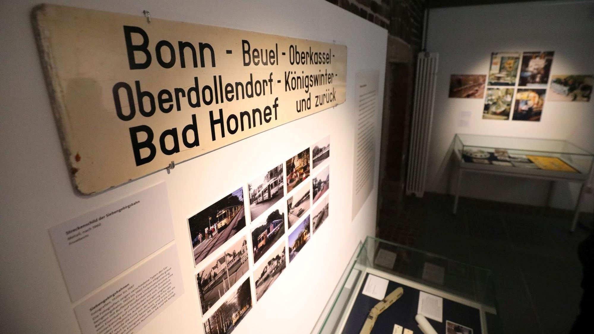 Ein Schild mit Ortsbezeichnungen über Fotos von Straßenbahnen.