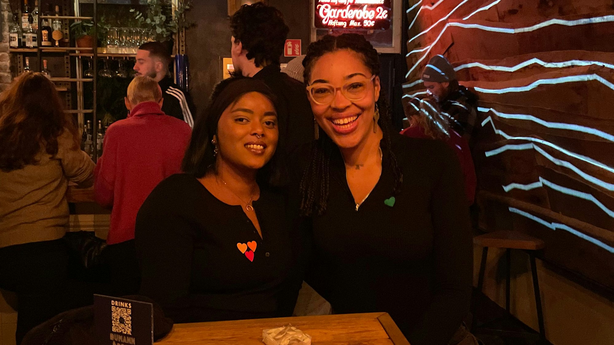 Finden Online-Dating anstrengend: Die Freundinnen Dora (l.) und Naemi sind zu Gast bei der Veranstaltung „Love At First Slide“ im Bumann & Sohn in Ehrenfeld. Die Herz-Sticker signalisieren den eigenen Status und Typ.