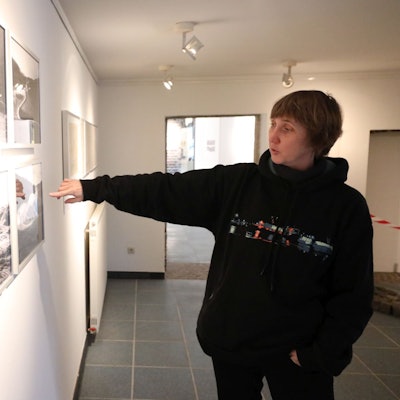 Eine Frau zeigt auf historische Fotos.