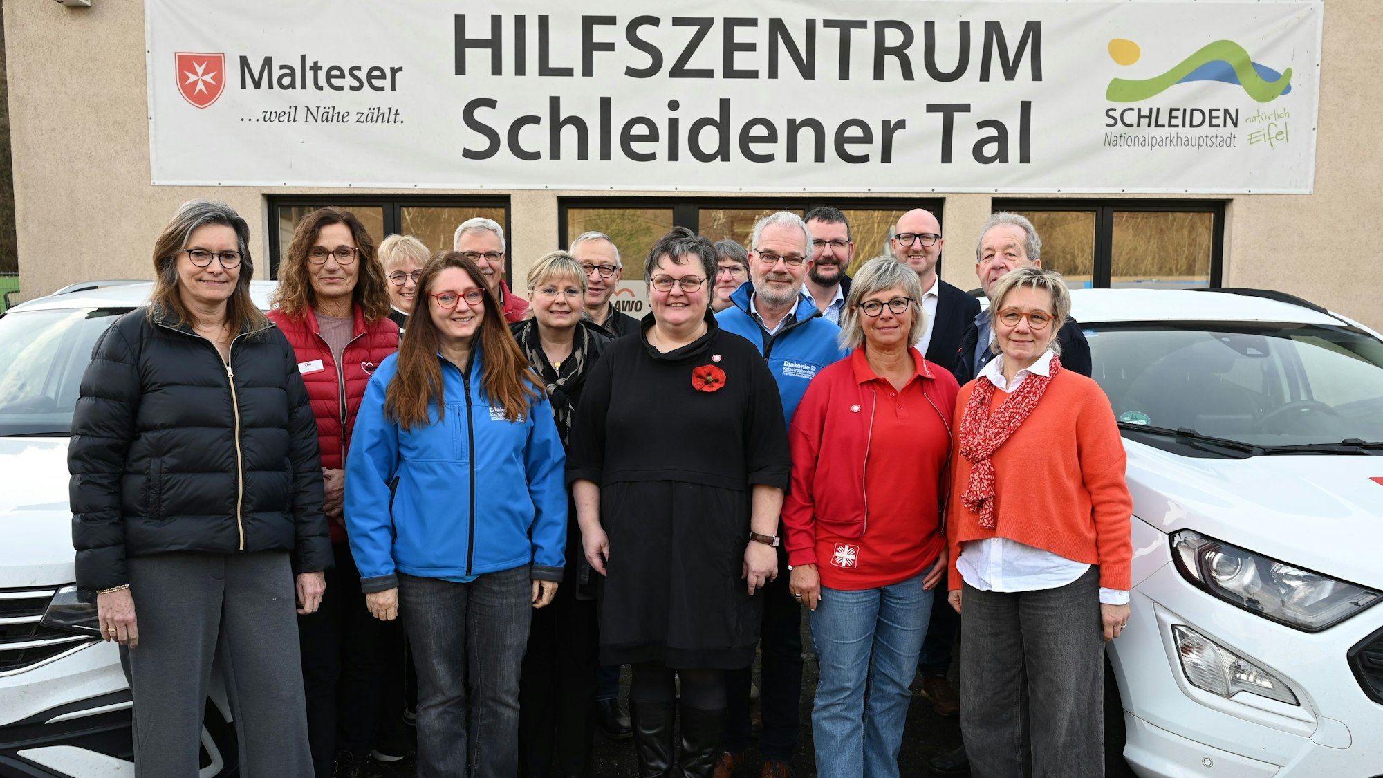 Einige Männer und Frauen stehen vor einem Gebäude in Gemünd, an dem ein Banner mit dem Schriftzug „Hilfszentrum Schleidener Tal“ hängt.