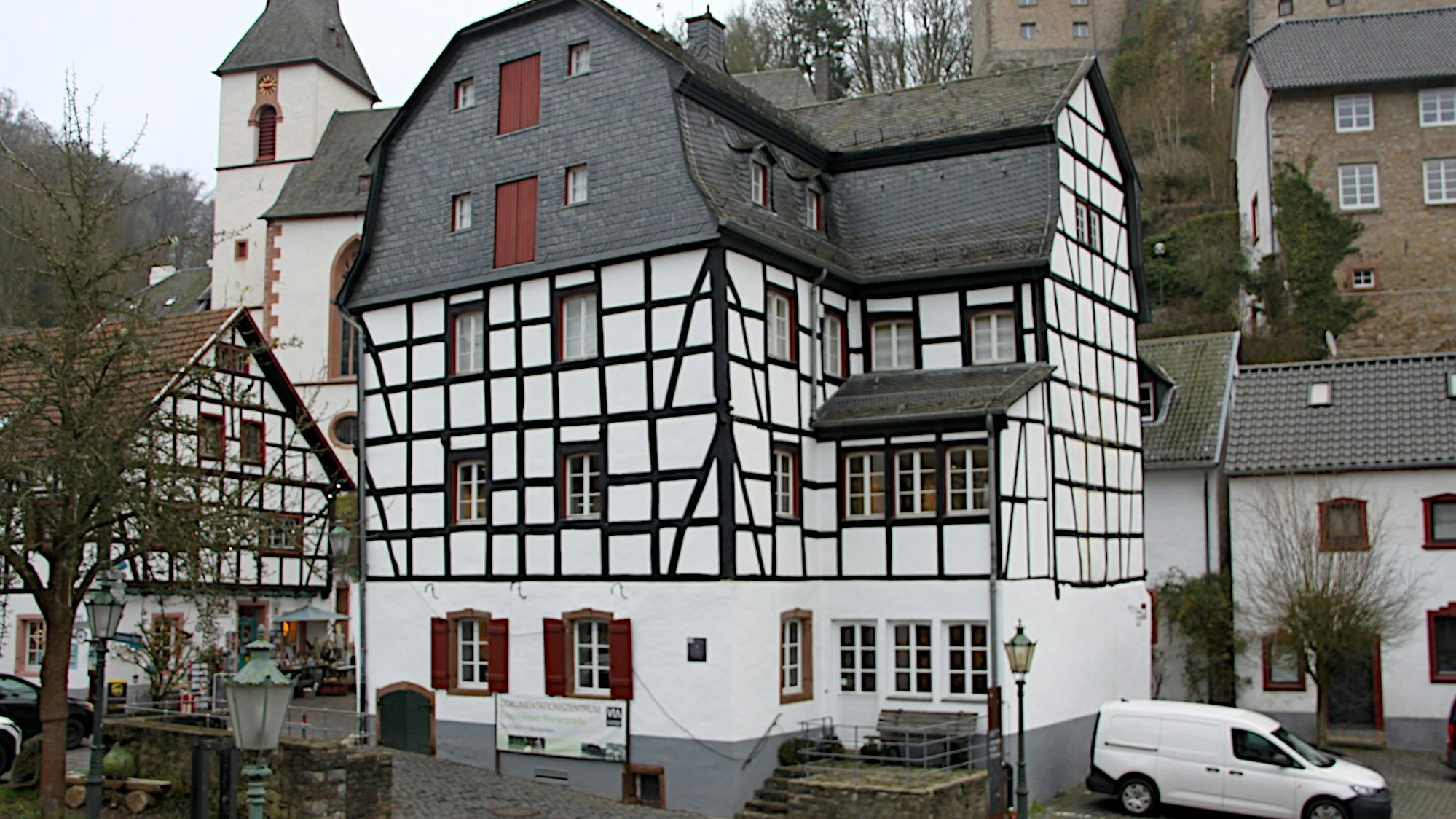 Beim Gildehaus handelt es sich um ein mehrstöckiges Fachwerkgebäude im Ortszentrum von Blankenheim. Im Hintergrund ist die Kirche zu sehen.