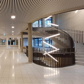 Ein leeres Foyer mit Treppen und glänzendem Boden.