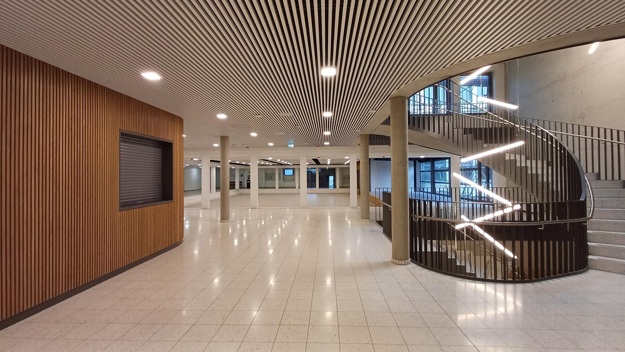 Ein leeres Foyer mit Treppen und glänzendem Boden.