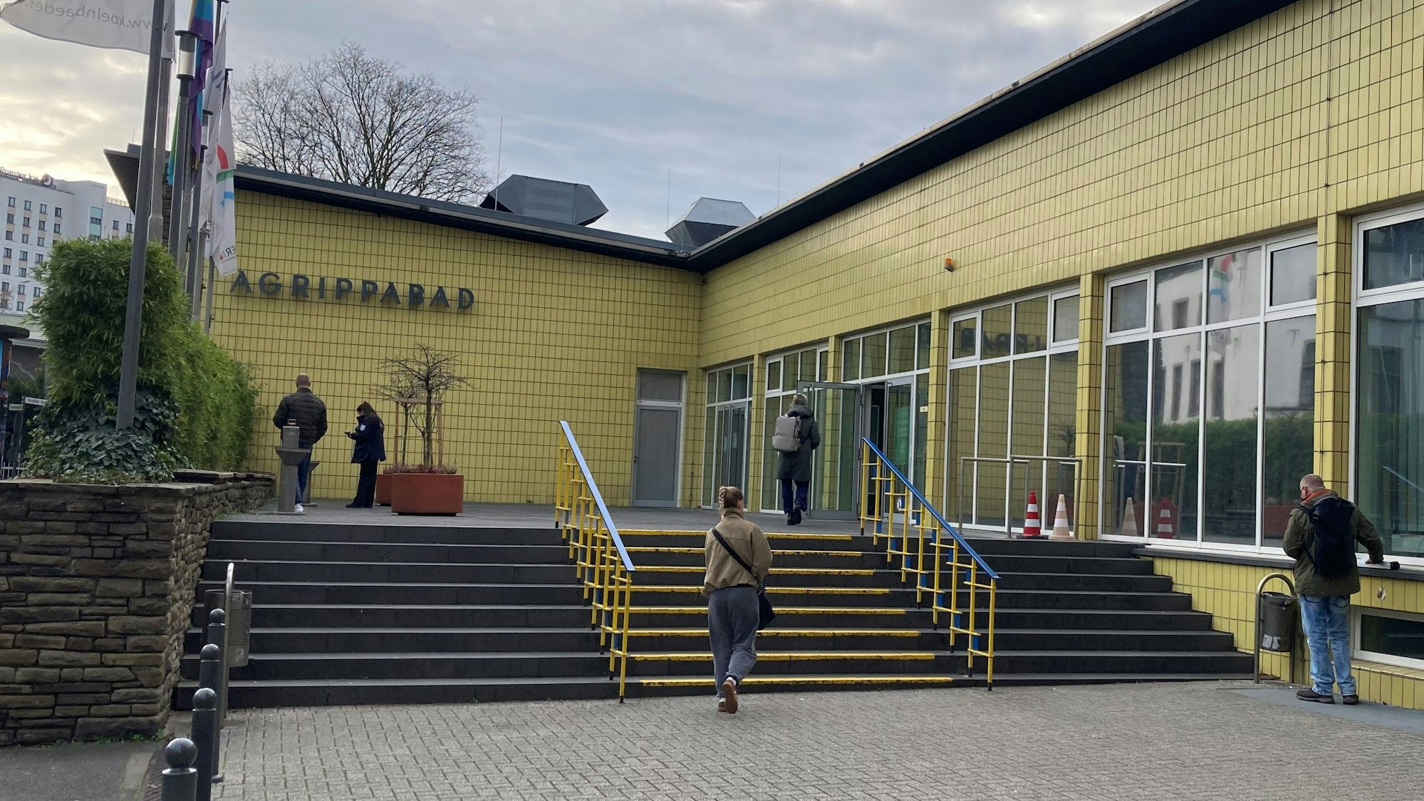 Menschen gehen die Treppe zu einem Schwimmbad hoch.