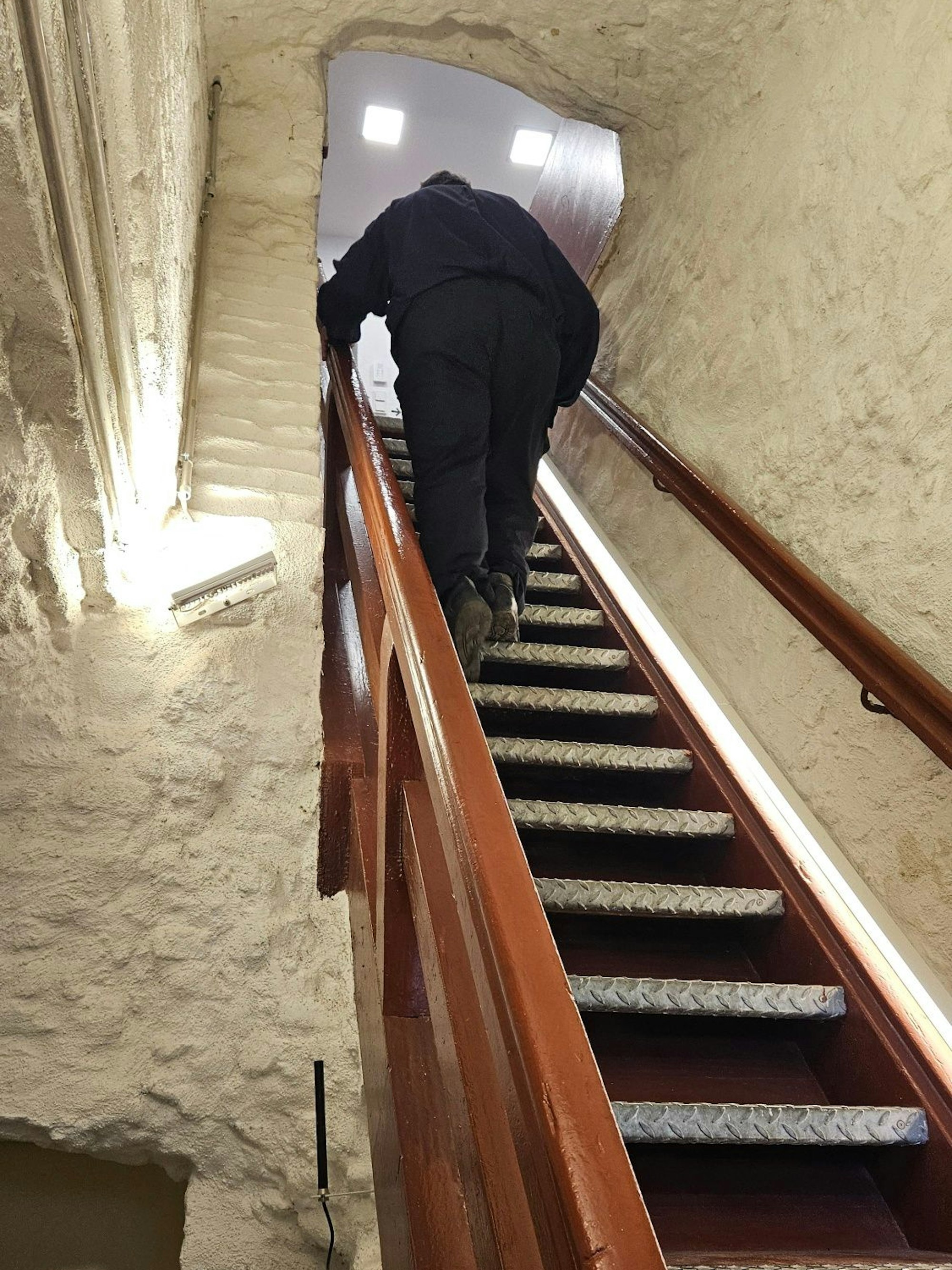 Zu sehen ist ein Mann auf einer steilen Treppe.