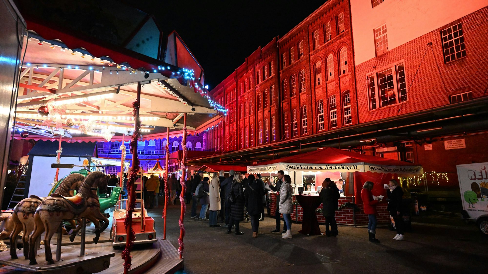 Ein Karussell steht vor einer rot angeleuchteten Wand.