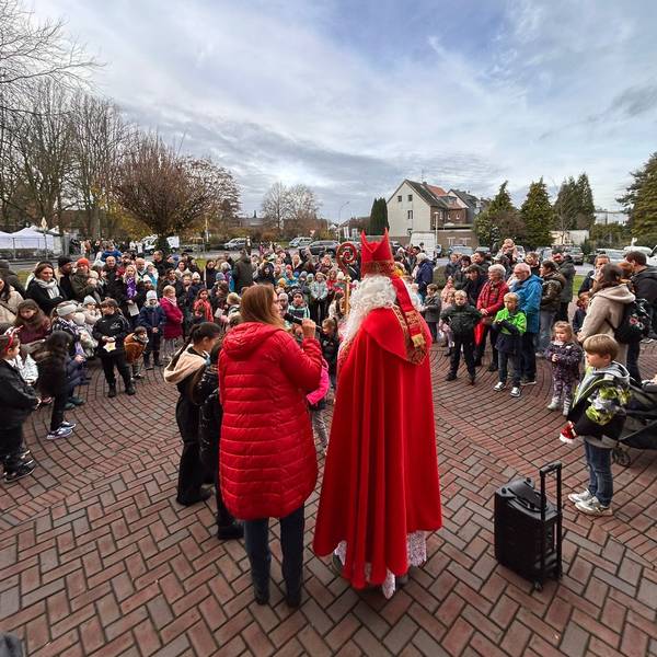 Auf dem Bild ist ein Nikolaus vor einer Menschengruppe zu sehen.