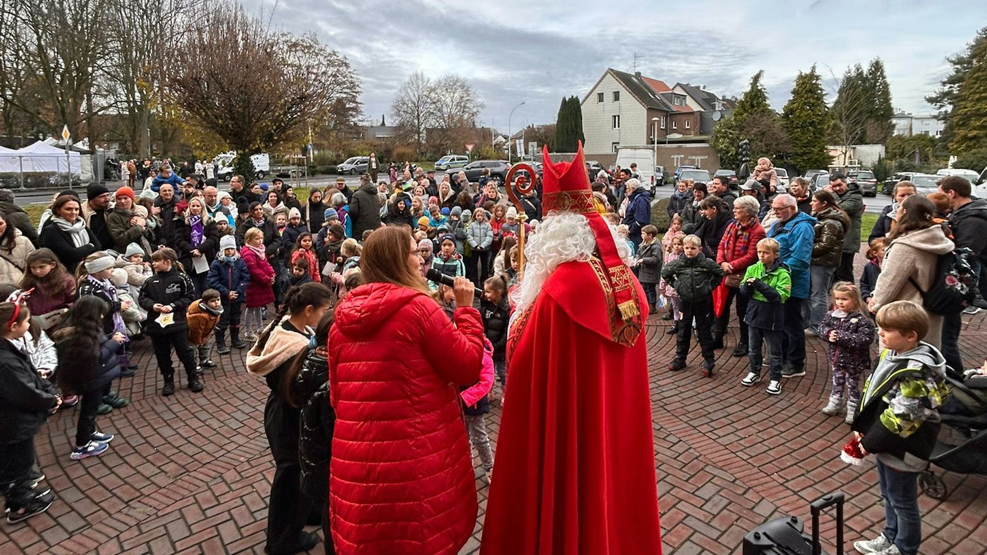 Auf dem Bild ist ein Nikolaus vor einer Menschengruppe zu sehen.