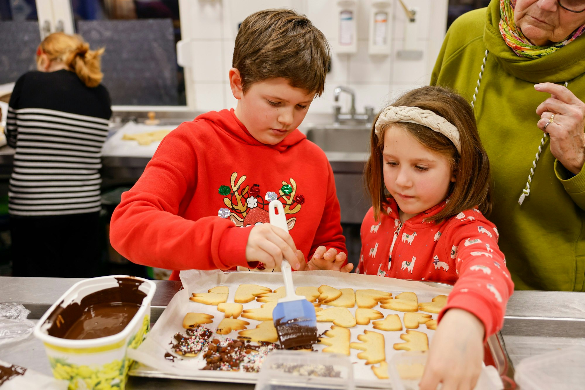Benno und Inga bestreichen andächtig die von ihnen ausgestochenen und gebackenen Kekse mit Schokolade.