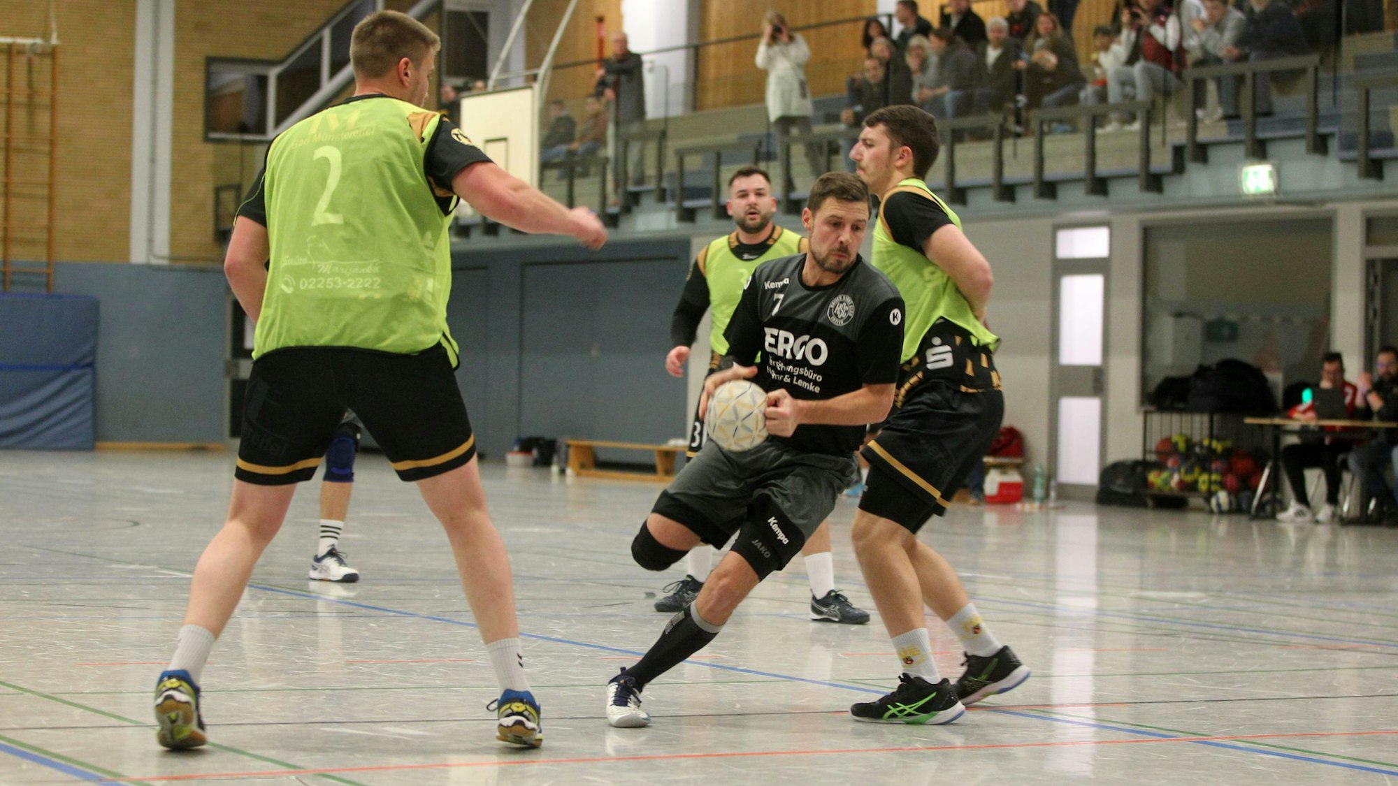 Ein Handballer des Kaller SC schiebt sich am Gegenspieler aus Bad Münstereifel (der TVE hat grüne Leibchen über den schwarzen Trikots) vorbei.