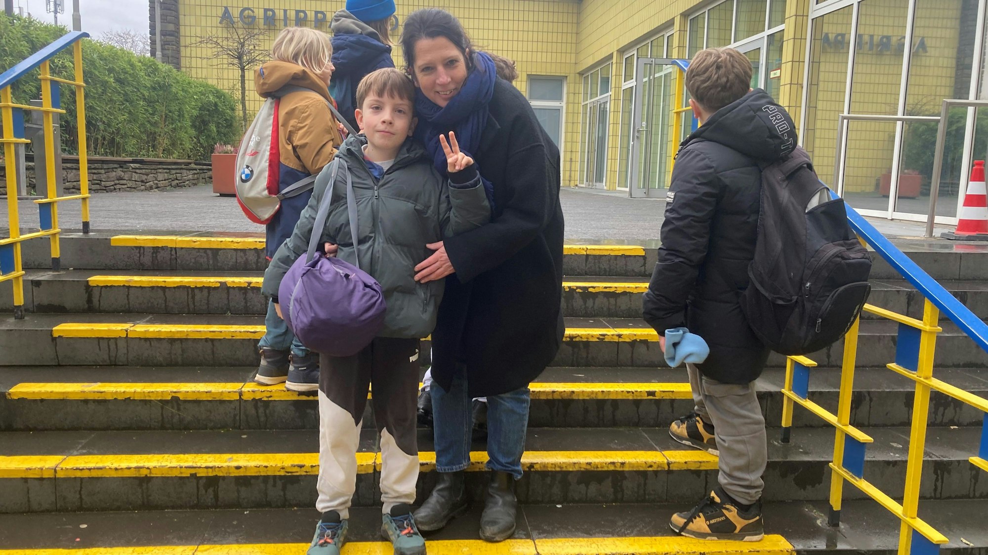 Ein Kind steht mit seiner Mutter auf einer Treppe.