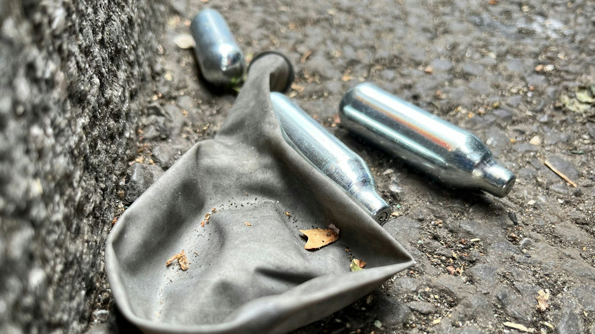 Eine Lachgas-Patrone und ein Luftballon liegen auf dem Boden.