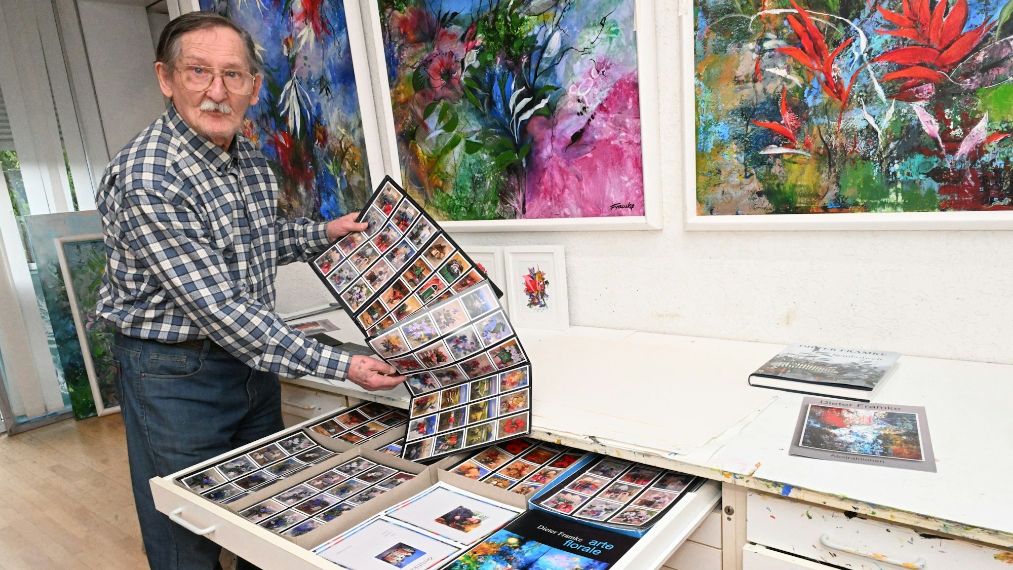 Dieter Framke zieht viele kleine Bilder aus einer Schublade.