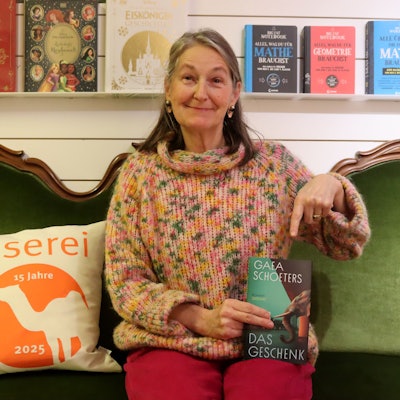 Das Bild zeigt Katharina Pütz, die auf einem grünen Sofa sitzt.