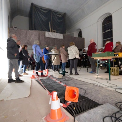 Menschen stehen in der Kirche und singen. Im Hintergrund ist die eingehauste Orgel zu sehen.