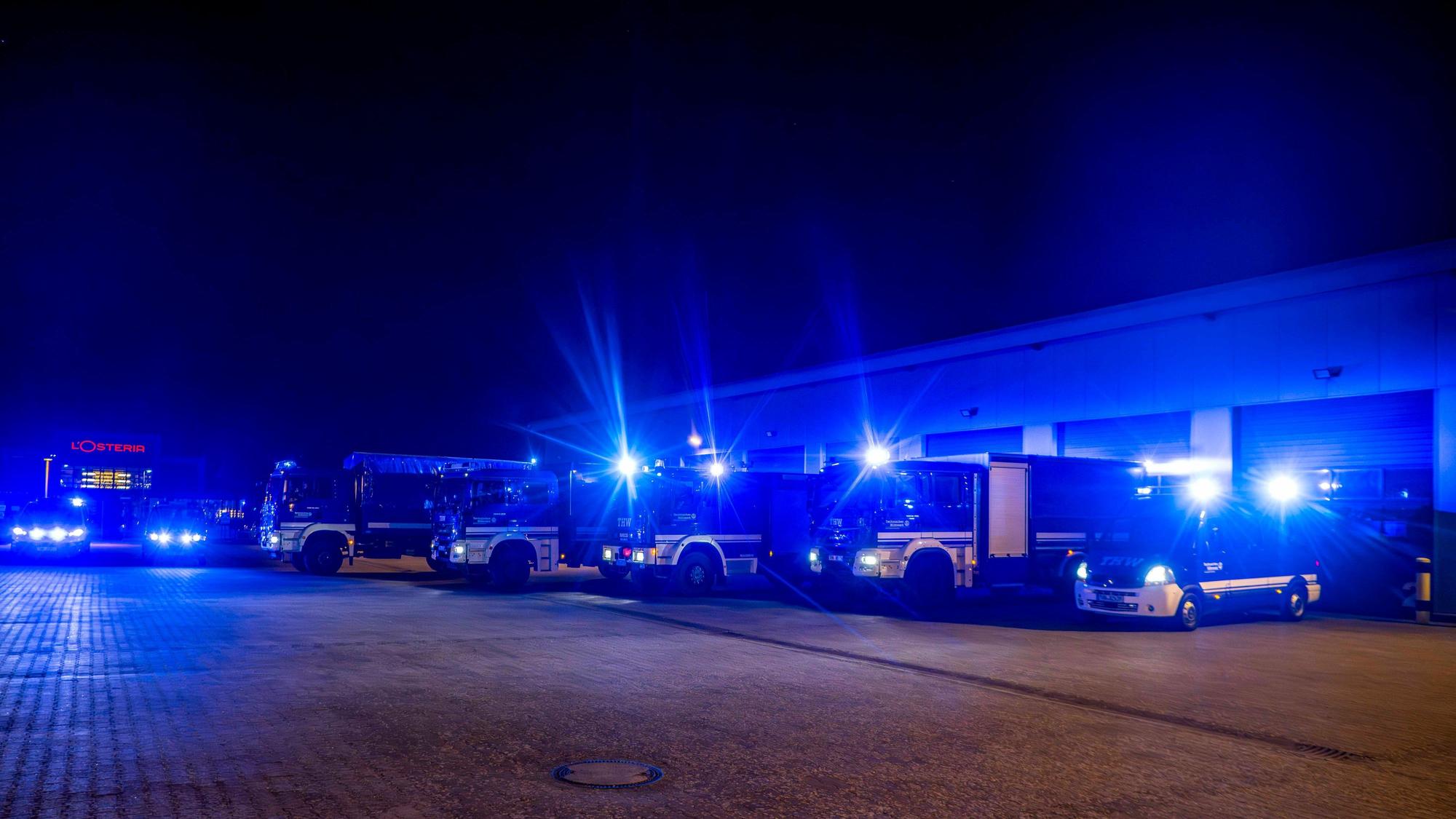 Das Foto zeigt mehrere Fahrzeuge des THW mit eingeschaltetem Blaulicht.