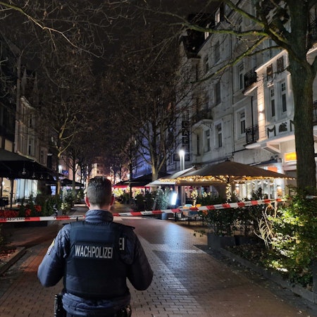 Ein Mitarbeiter der Wachpolizei steht an einem Absperrband in der Innenstadt.