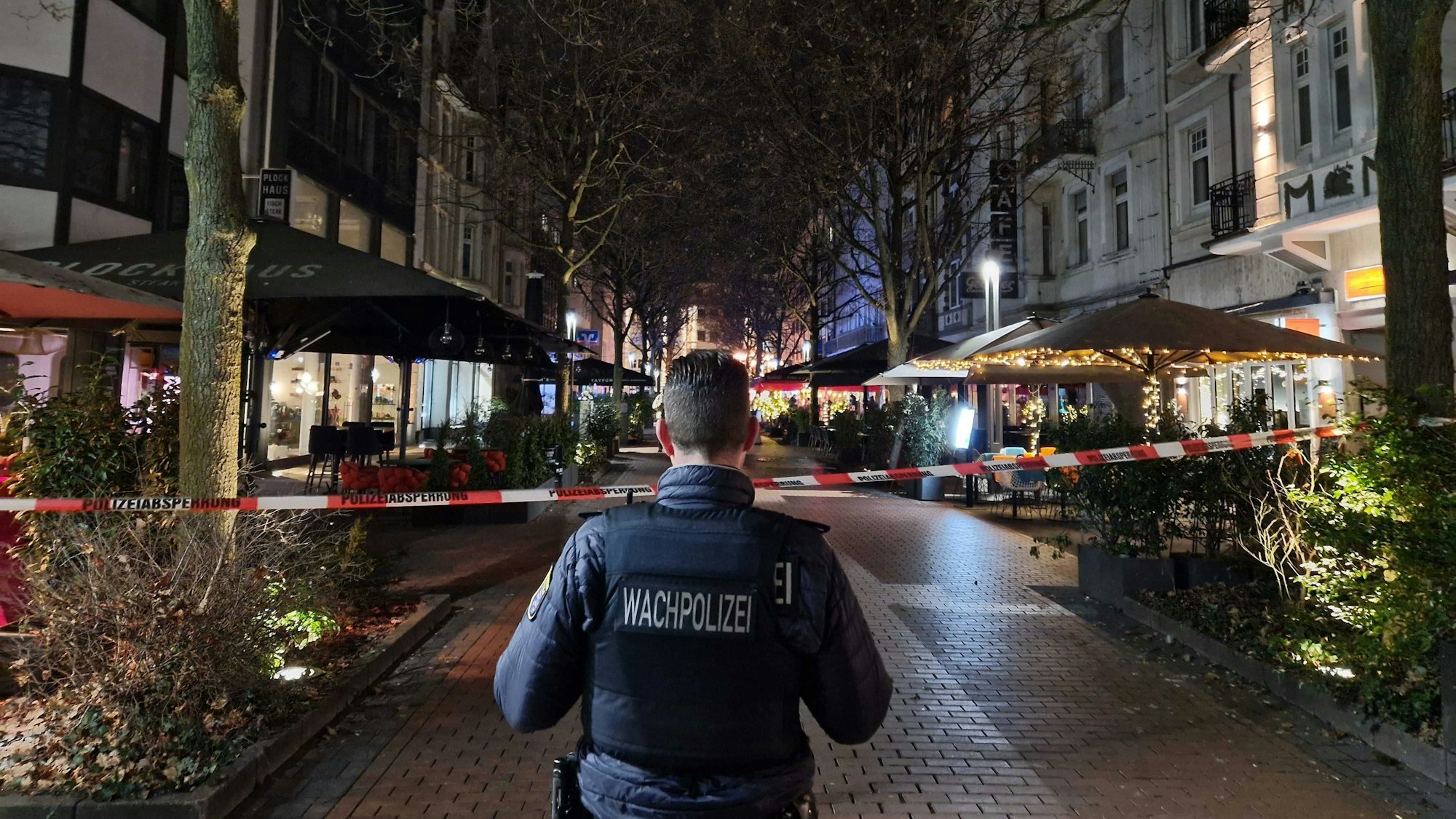 Ein Mitarbeiter der Wachpolizei steht an einem Absperrband in der Innenstadt.