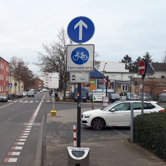 Ein Schild am Straßenrand weist einen die daneben liegende Straße als Fahrradstraße aus.