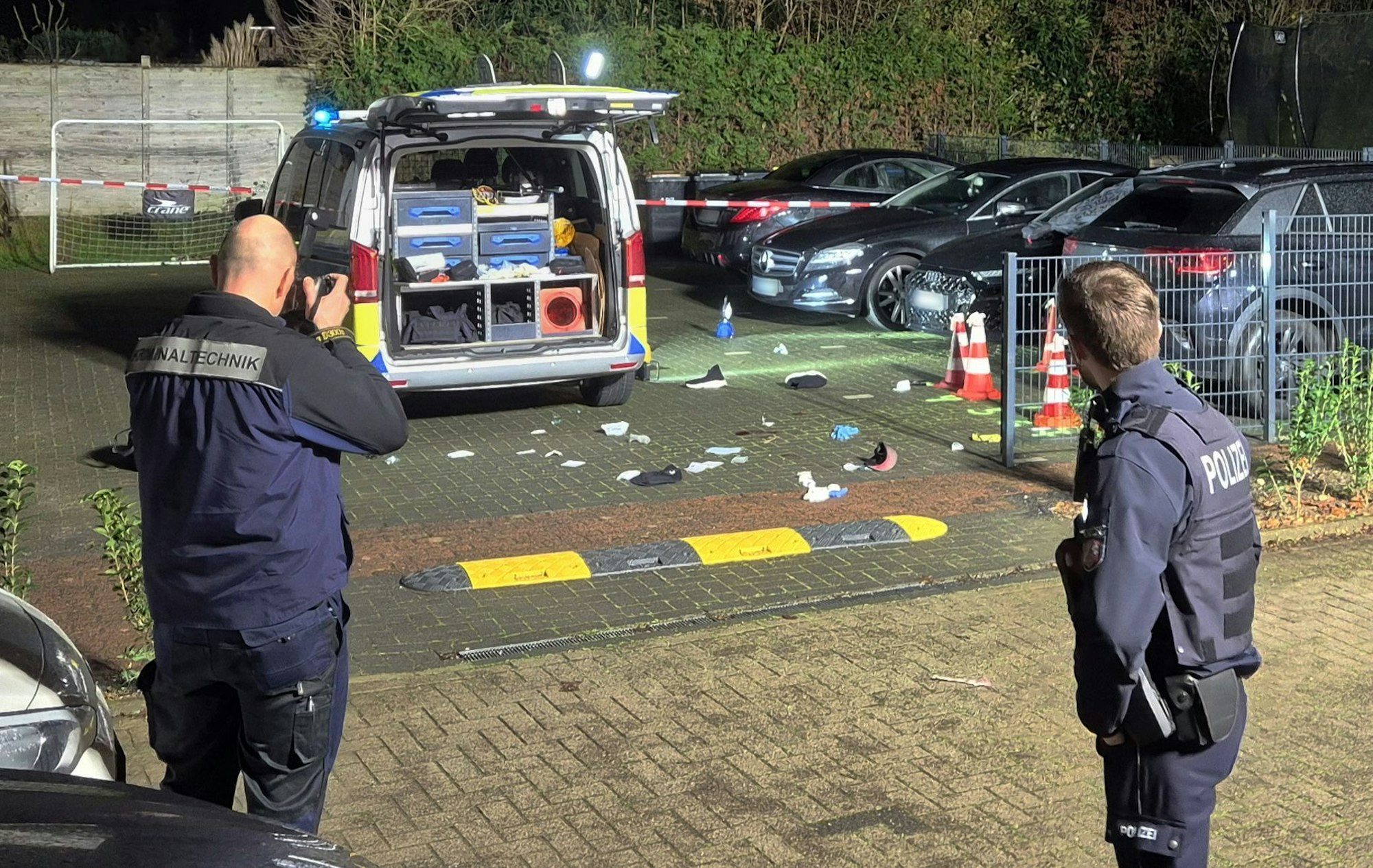 21.12.2025, Nordrhein-Westfalen, Köln: Einsatzkräfte der Polizei und der Kriminaltechnik arbeiten an einem Tatort. Ein Mann wurde dort durch die Windschutzscheibe eines Autos, in dem er saß, angeschossen.