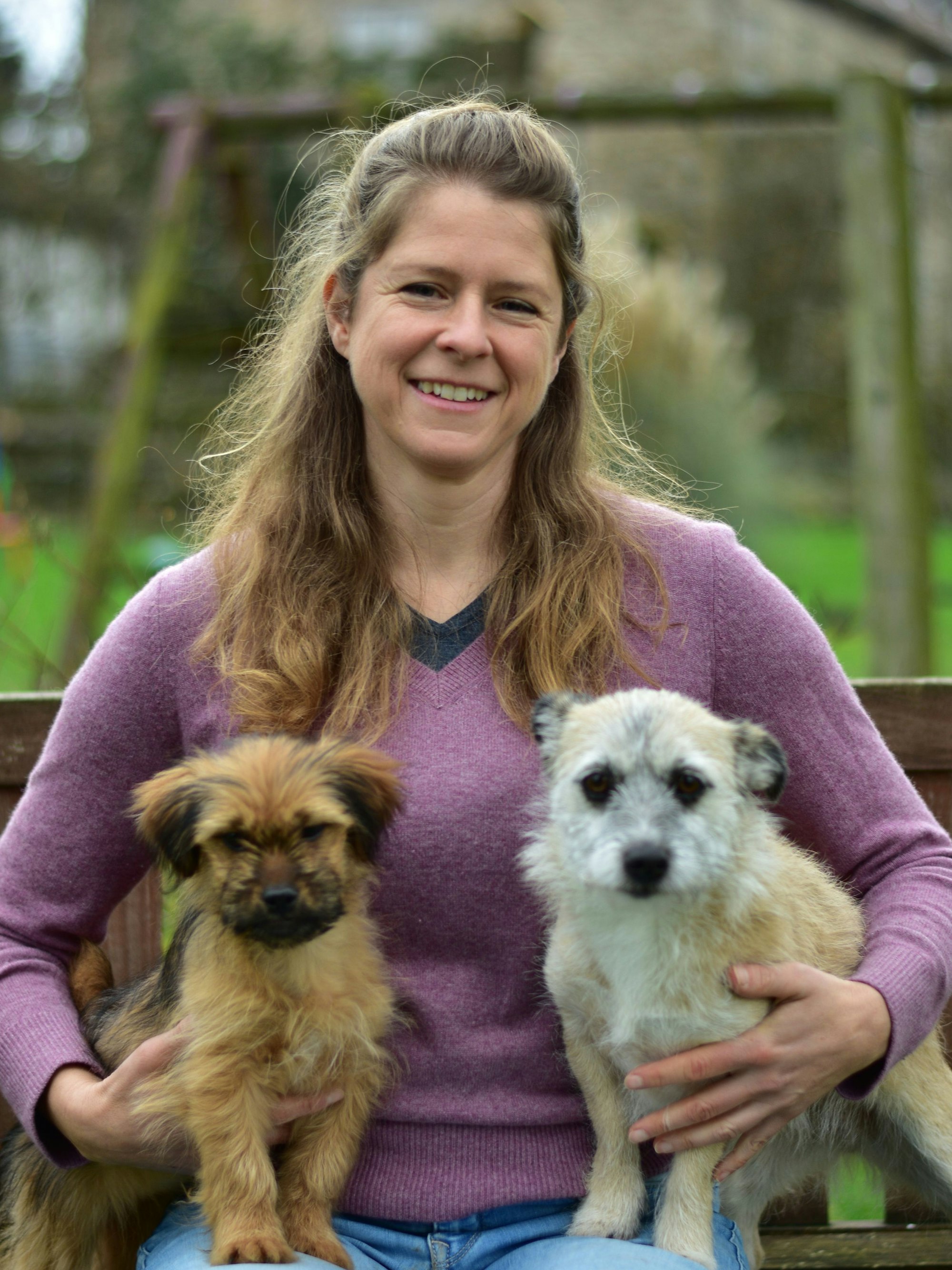 Eine Frau mit zwei Hunden auf dem Schoß.