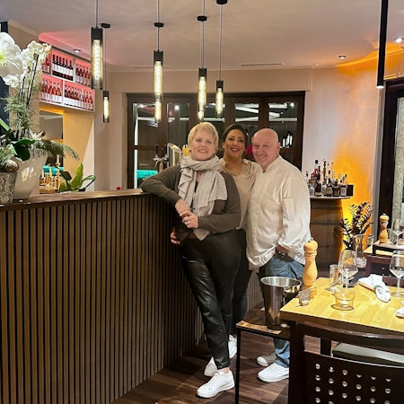 Zwei Frauen und ein Mann stehen an einer Theke in einem Restaurant.