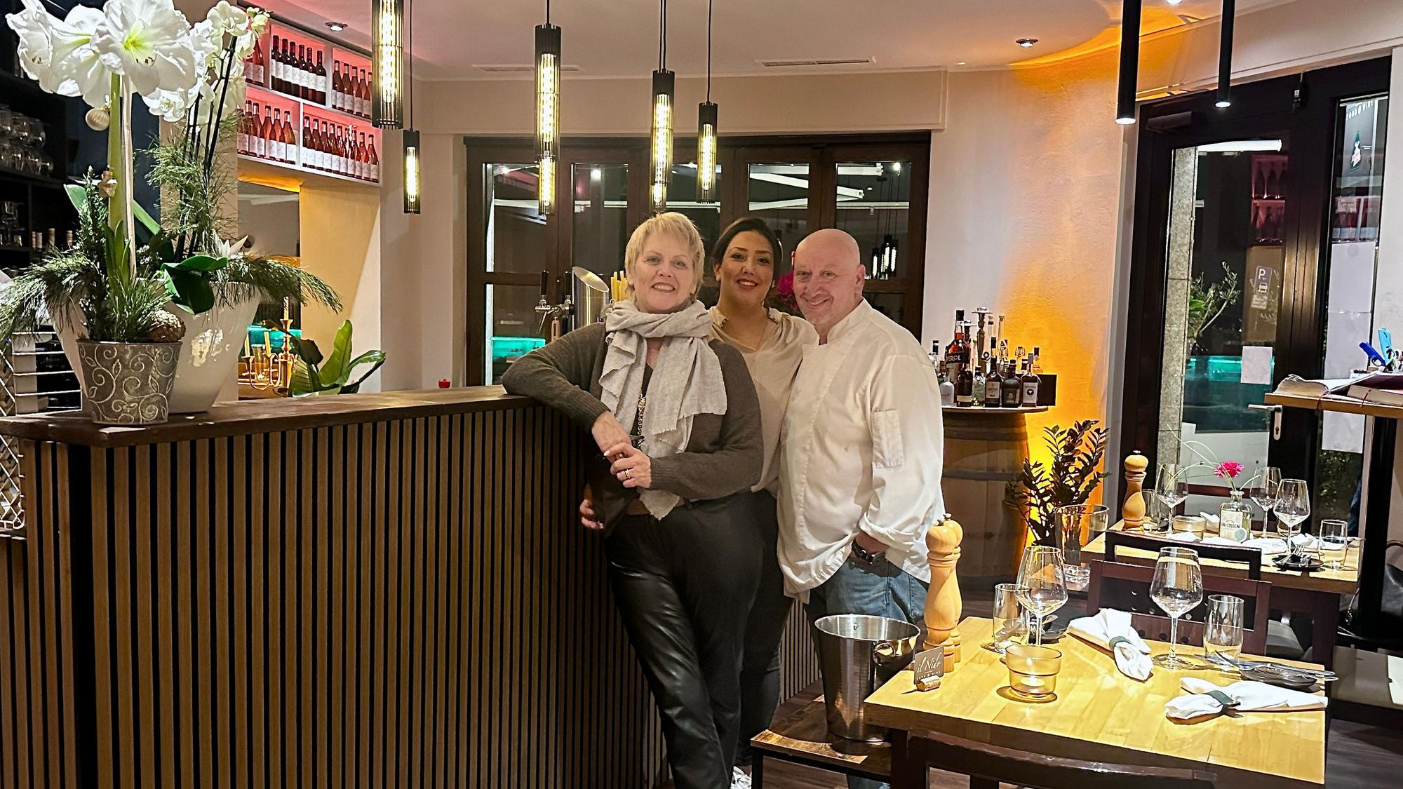 Zwei Frauen und ein Mann stehen an einer Theke in einem Restaurant.