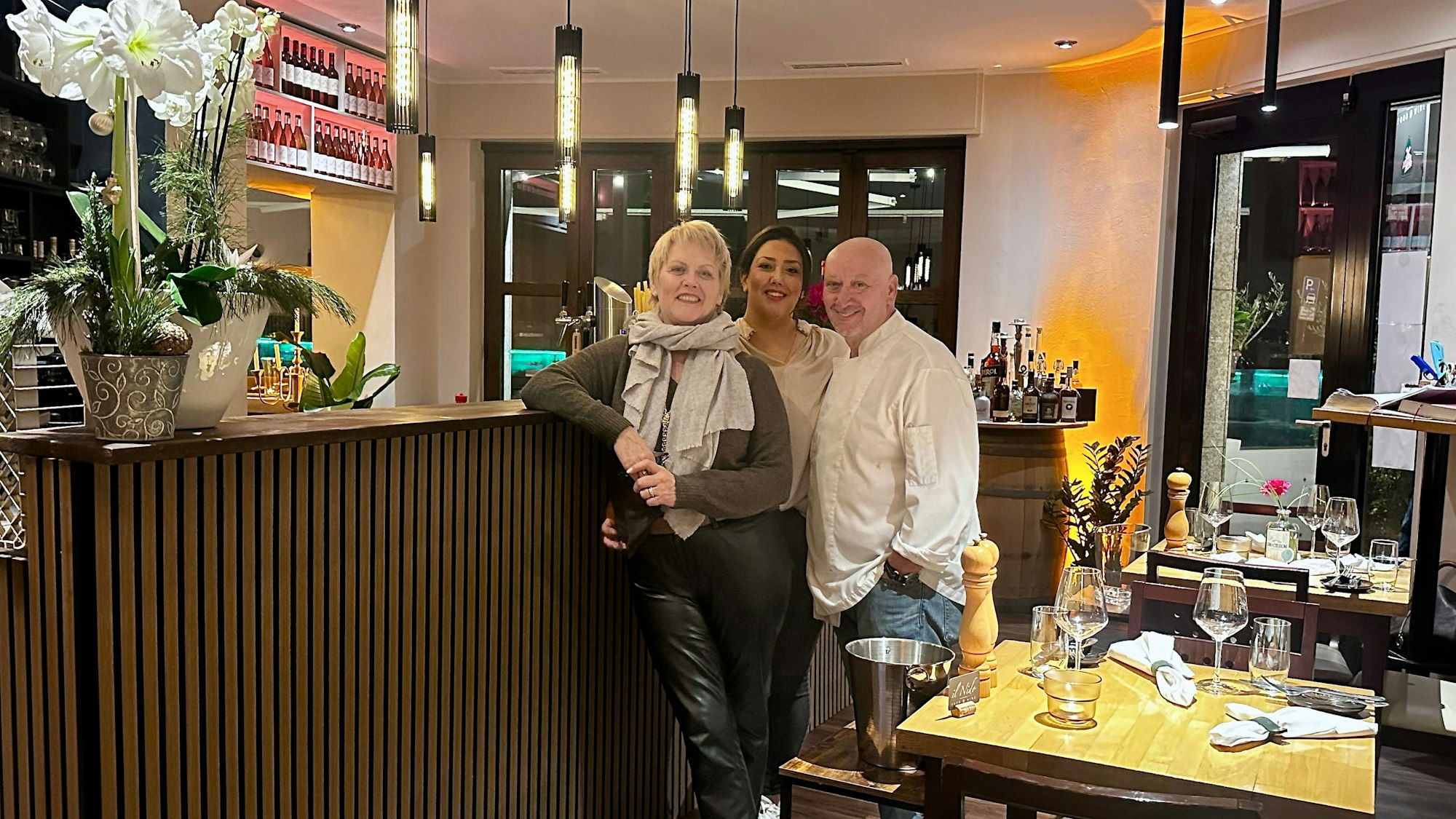 Zwei Frauen und ein Mann stehen an einer Theke in einem Restaurant.