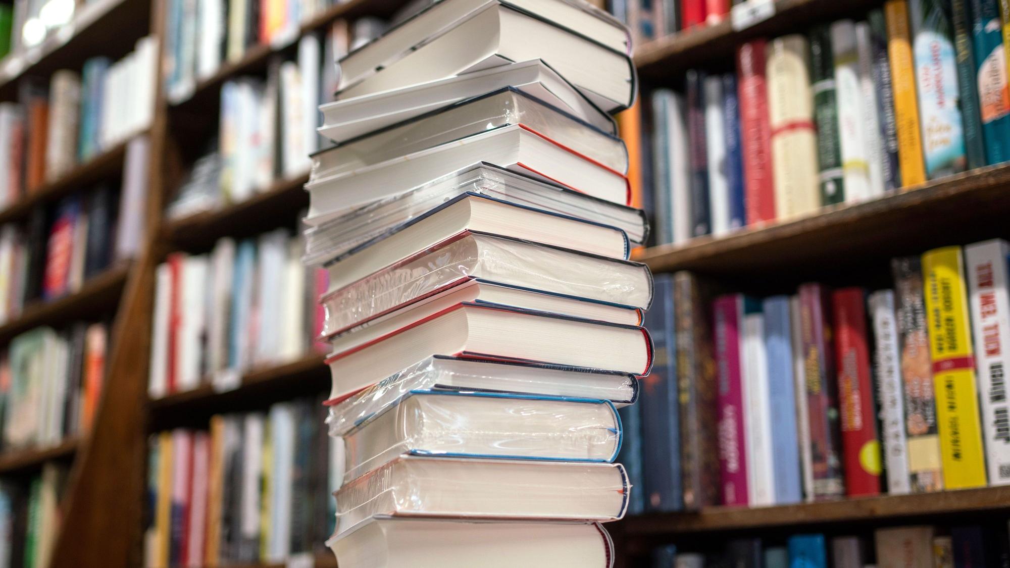 Ein Stapel neuer Bücher liegt auf einem Verkaufstisch in einer Buchhandlung.