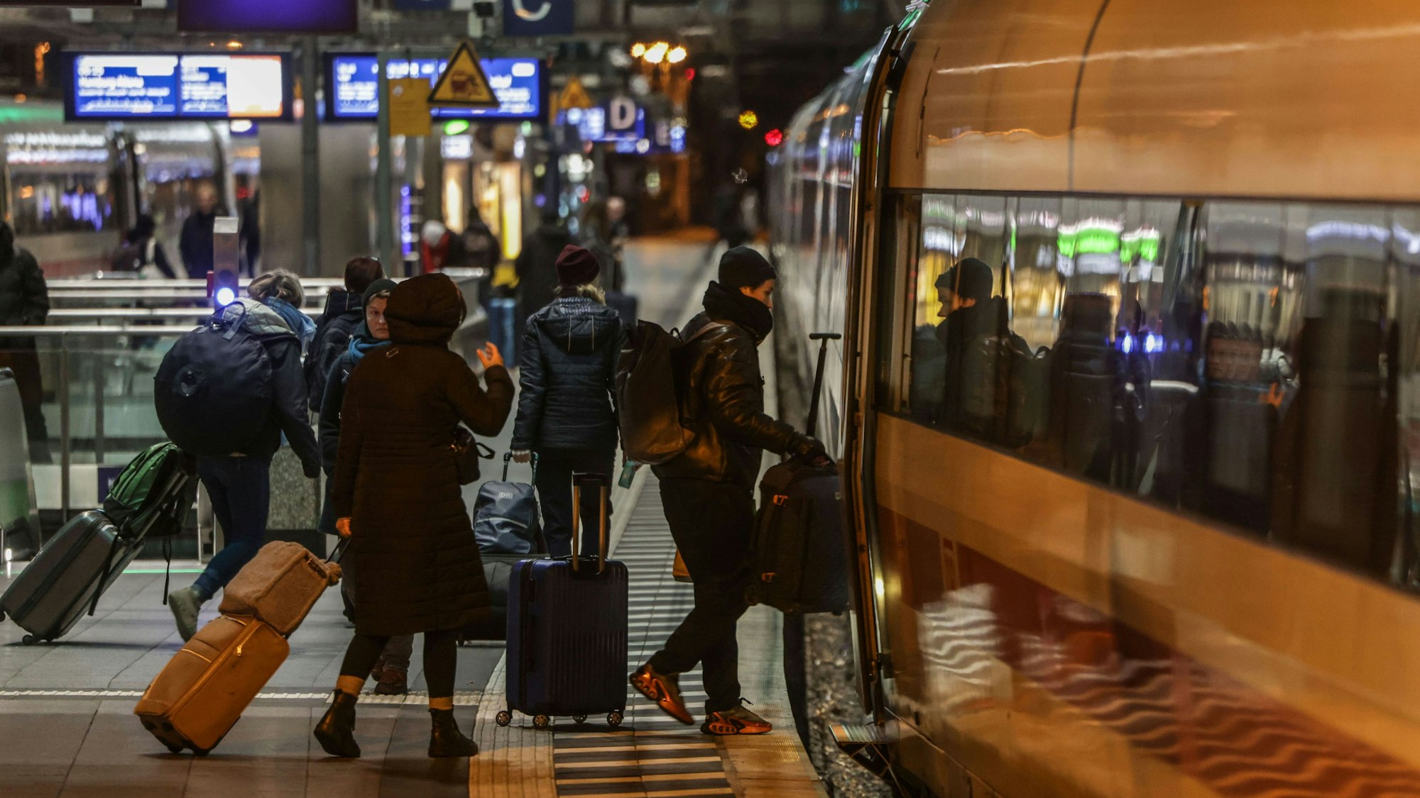 Menschen stehen mit ihren Koffern auf einem Bahnsteig der Kölner Hauptbahnhof und steigen in einen ICE.