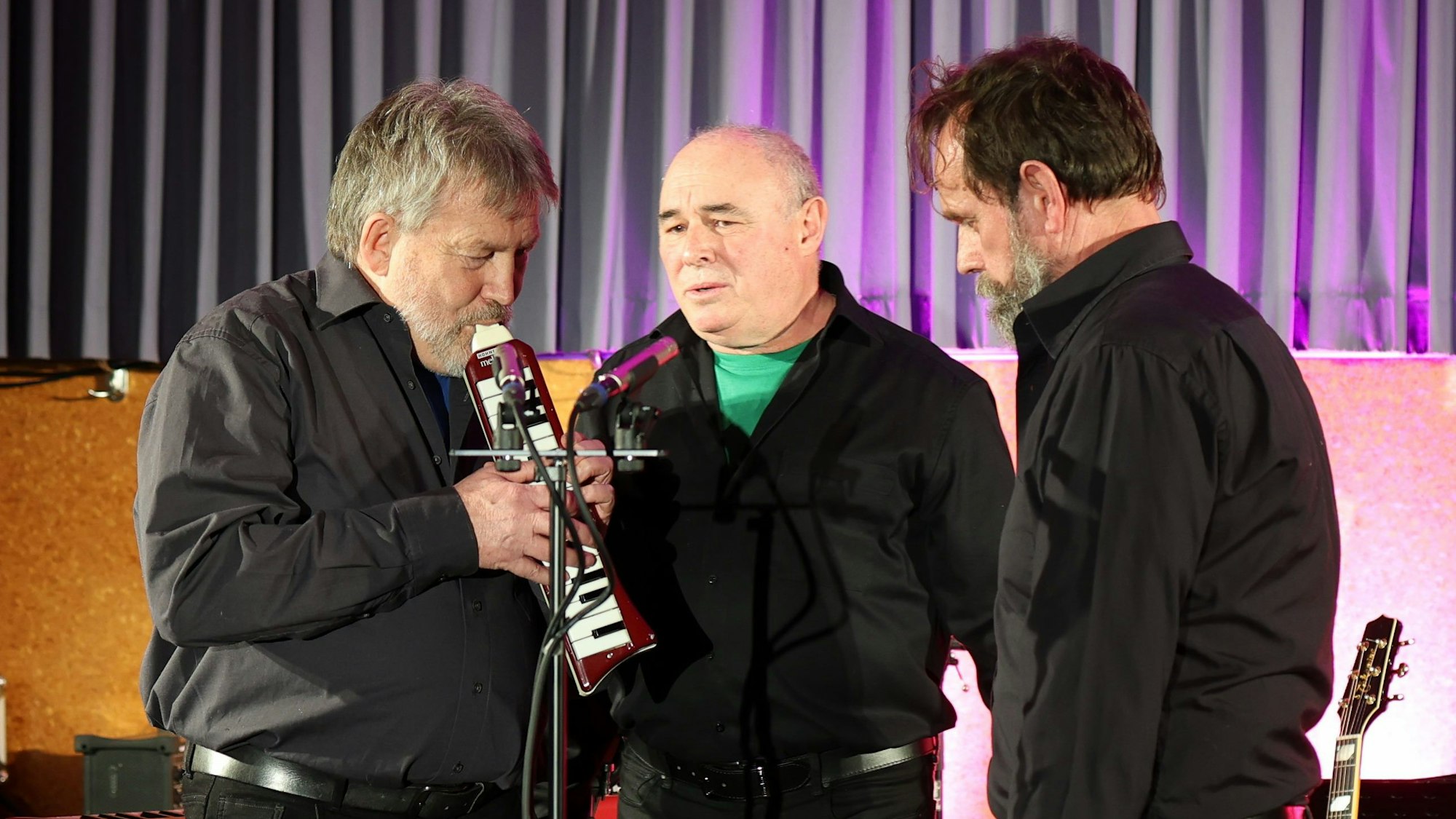 Drei Männer des Trios EU-Semble stehen um ein Mikrofon.