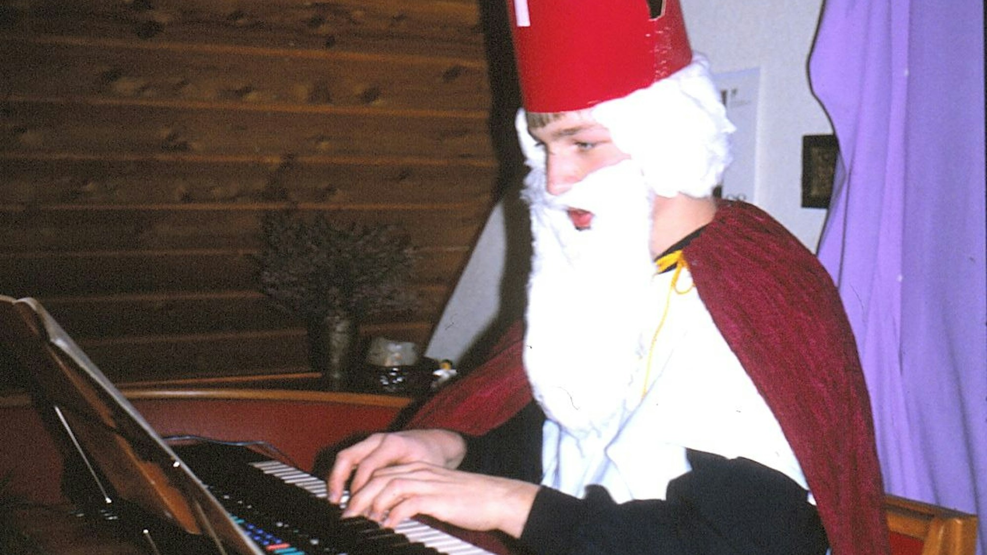 Ein Jugendlicher sitzt verkleidet als Nikolaus am Keyboard.