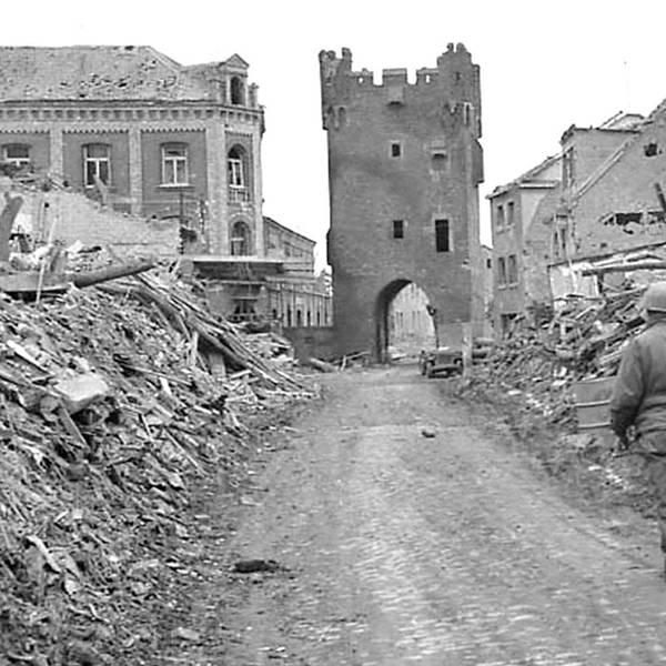 Ein Soldat geht zwischen Trümmerbergen auf das Stadttor zu.