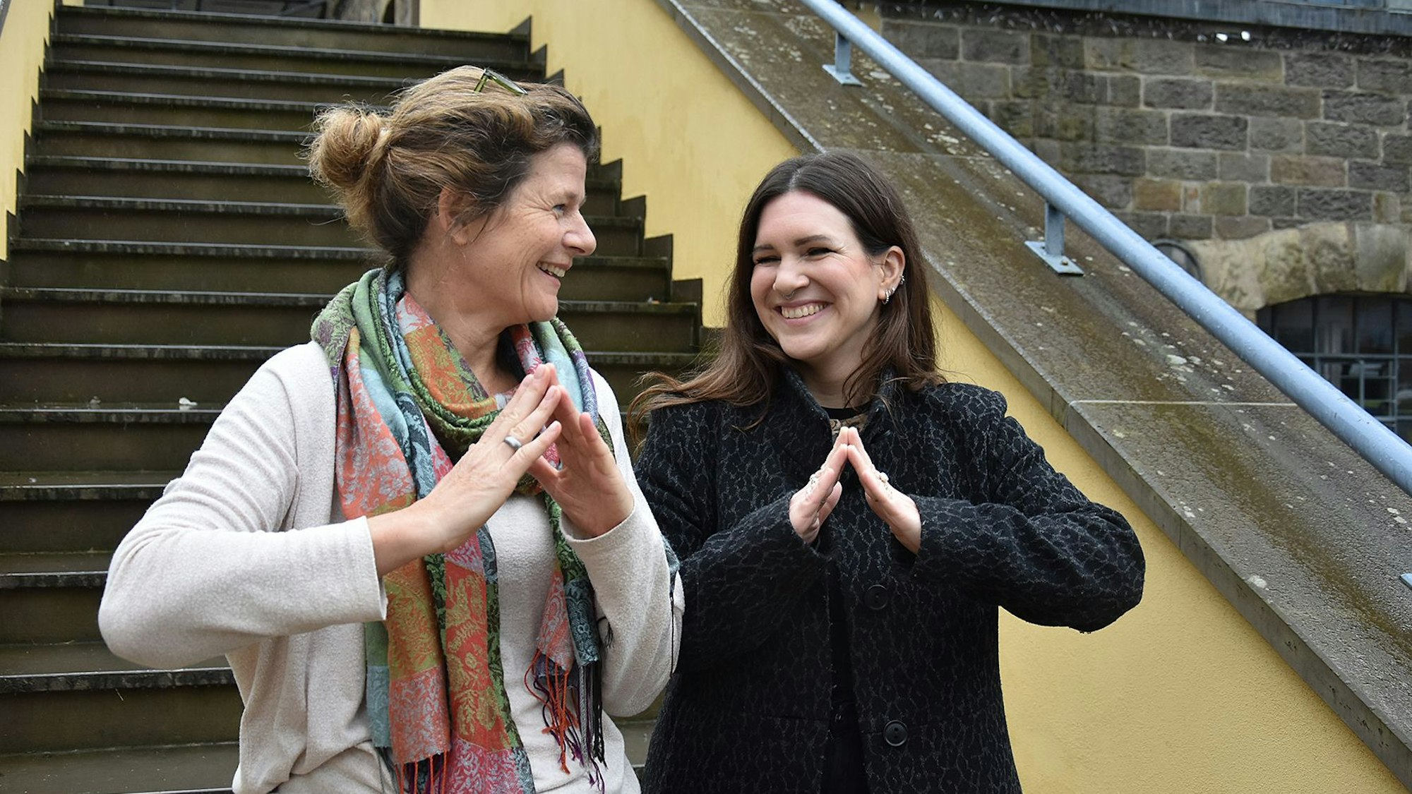 Zwei Frauen bilden mit ihren Händen ein symbolisches Dach.