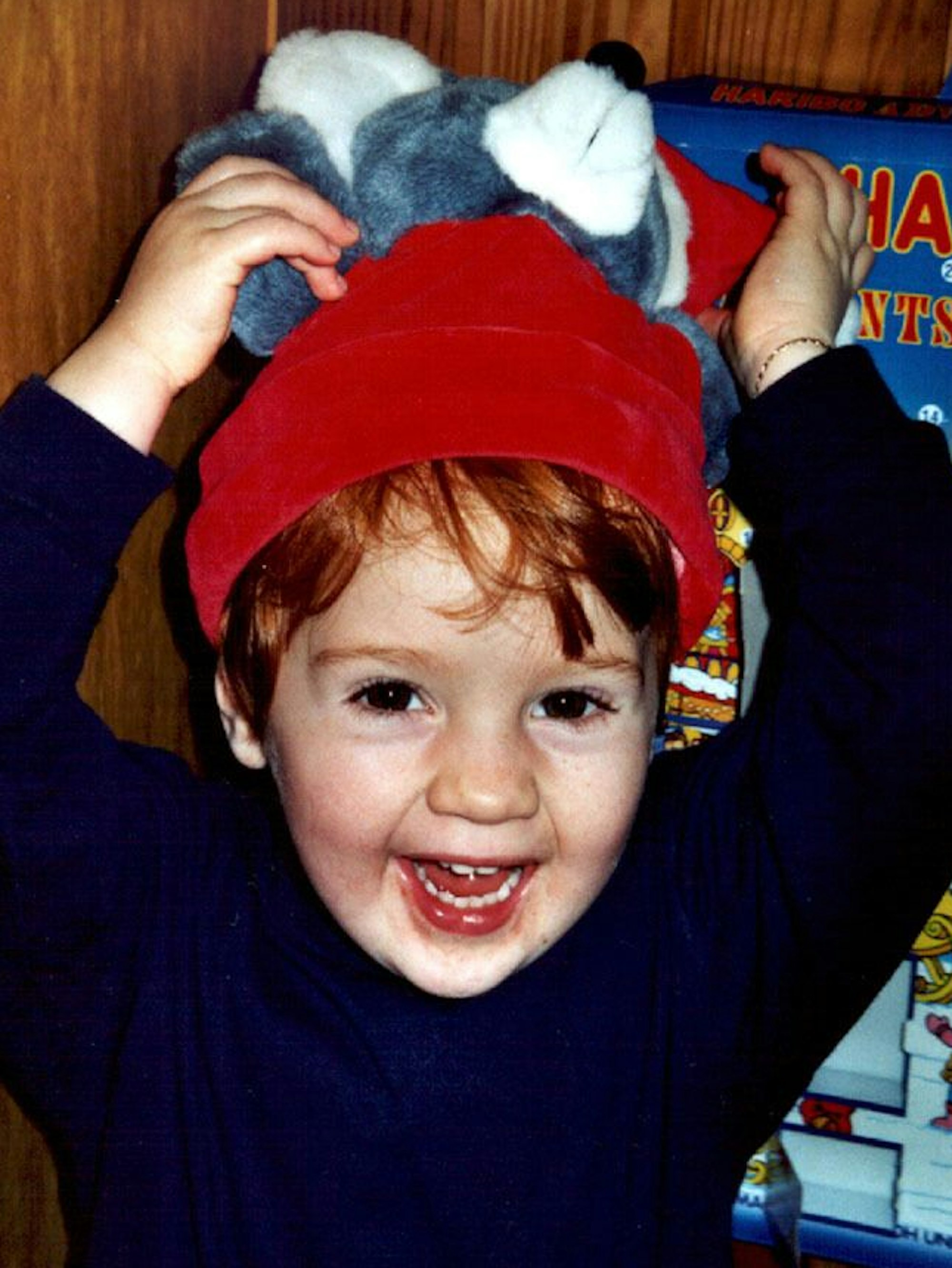 Ein kleiner Junge mit einer Nikolausmütze auf dem Kopf grinst in die Kamera.