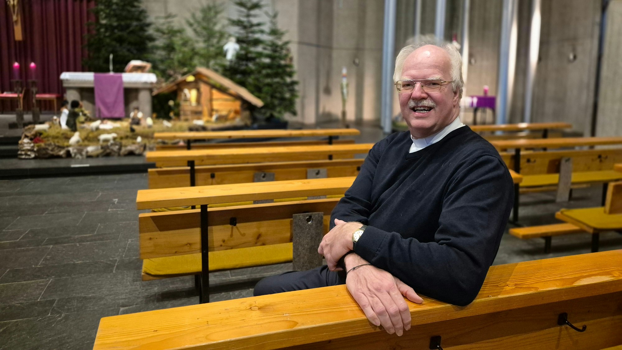 Ein Priester sitzt in einer Kirchenbank.