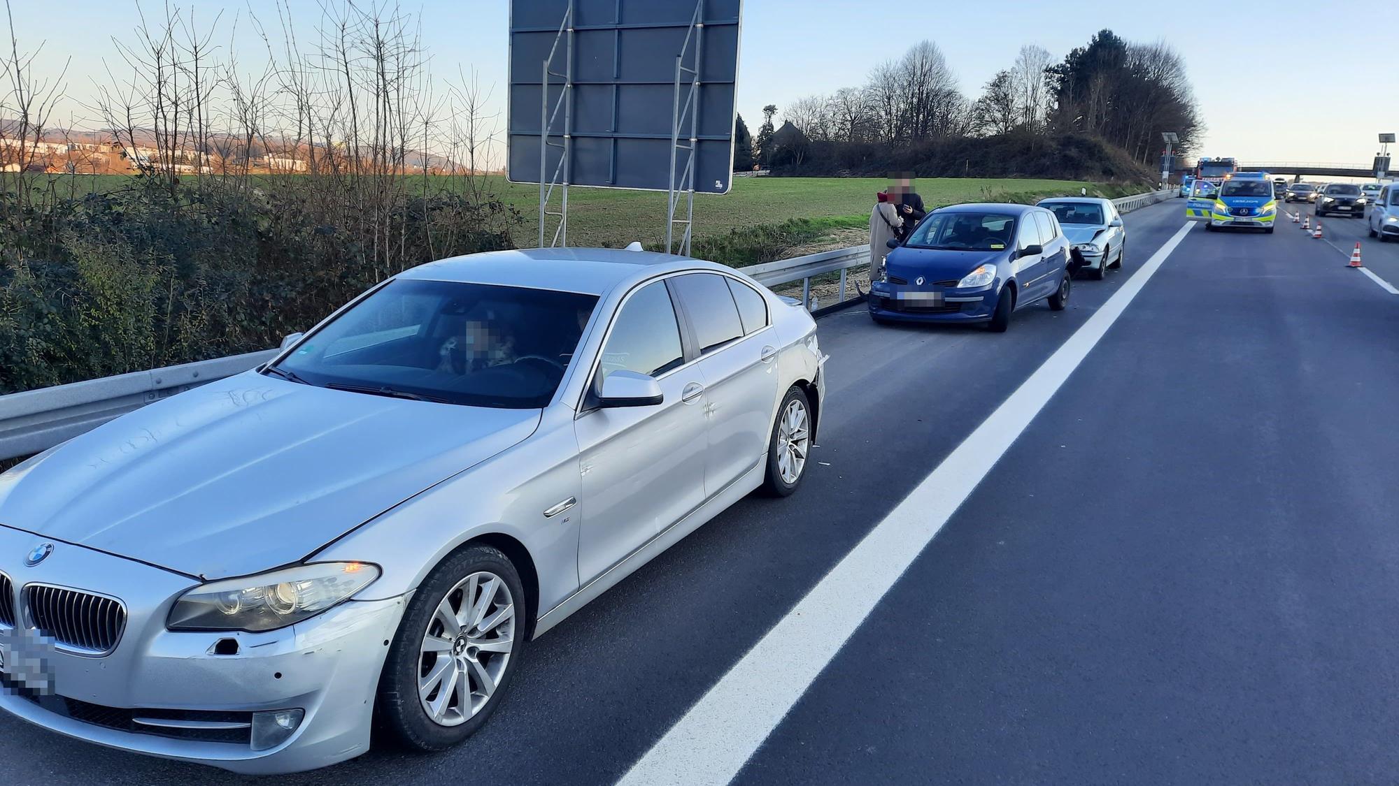 Drei Autos auf dem Standstreifen einer Autobahn, im Hintergrund ein Polizeifahrzeug.