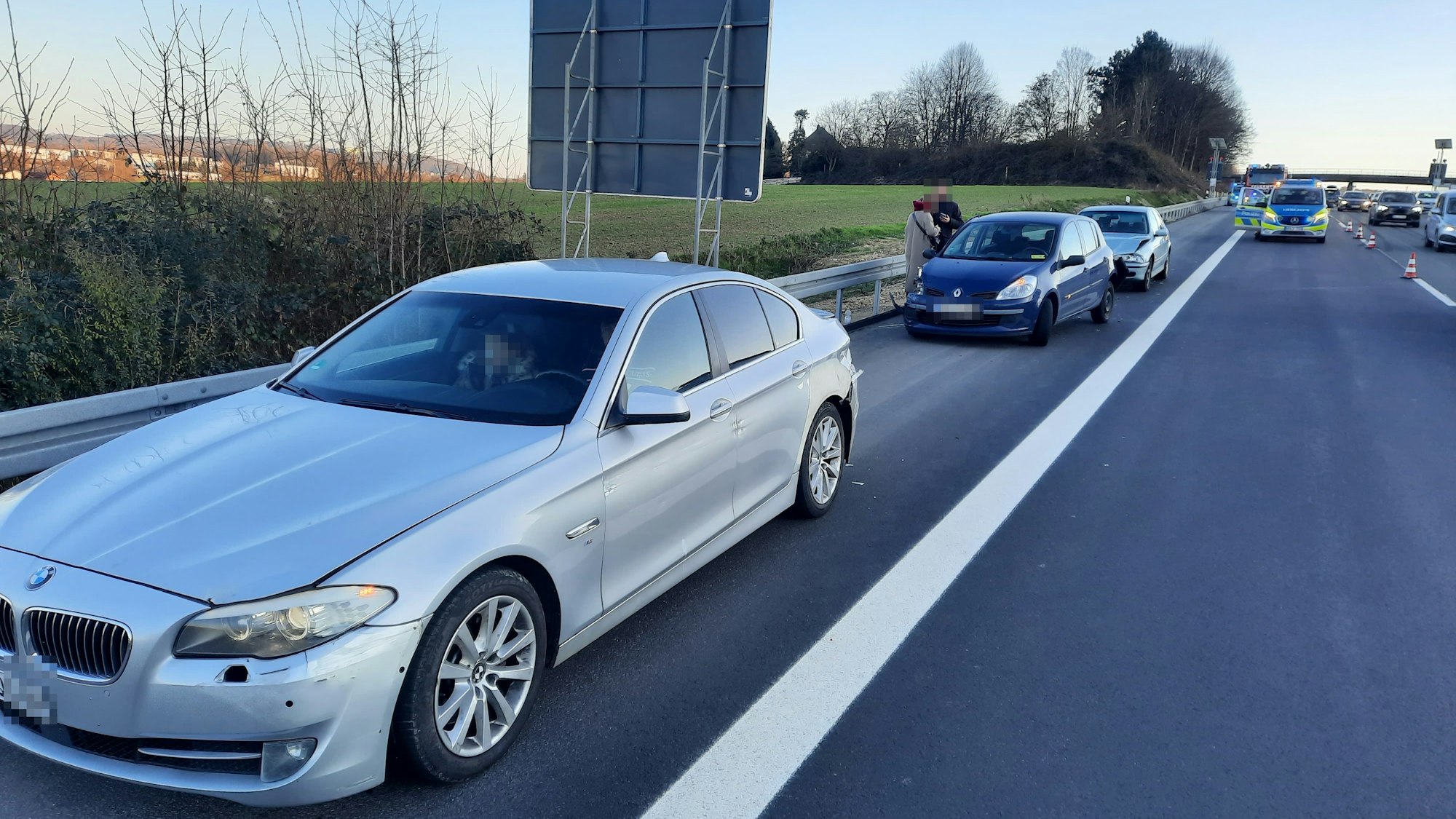 Drei Autos auf dem Standstreifen einer Autobahn, im Hintergrund ein Polizeifahrzeug.