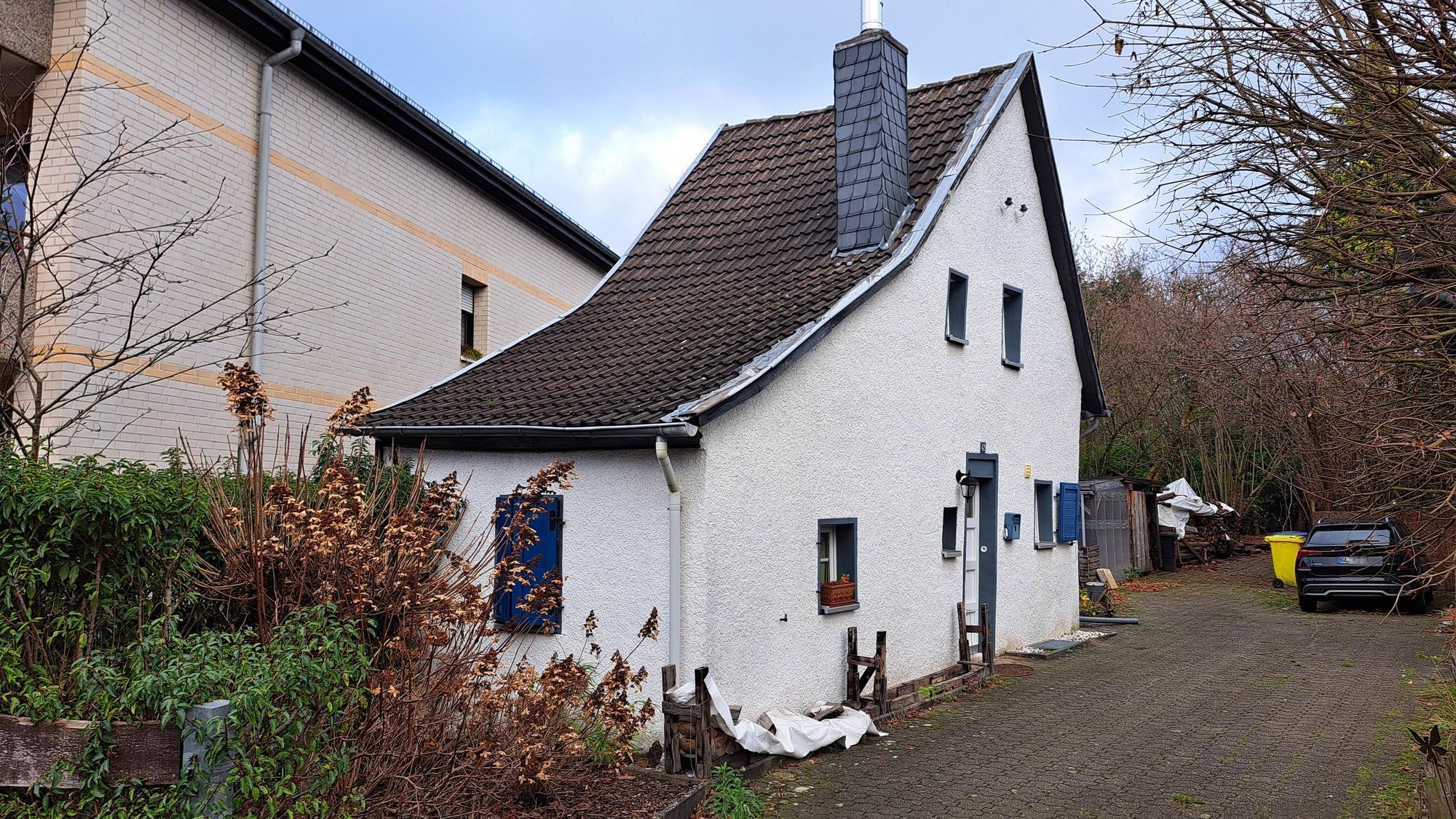 Eine gerade mal ein Zimmer breites Haus steht auf einem größeren Grundstück.