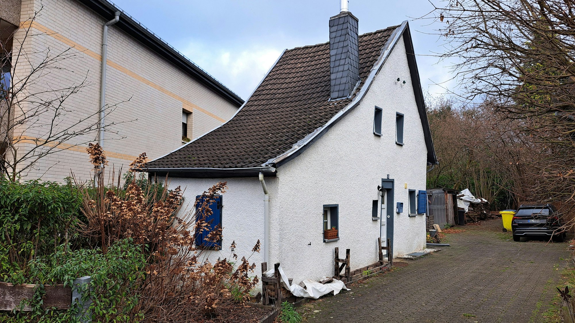 Eine gerade mal ein Zimmer breites Haus steht auf einem größeren Grundstück.