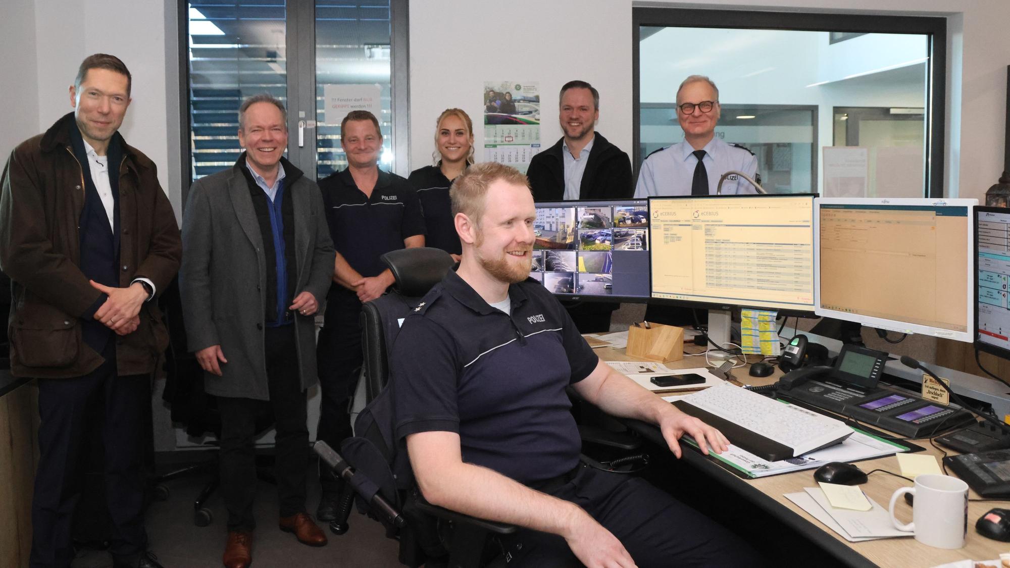 Eine Gruppe im Hintergrund, vorn ein Mann am Computerterminal.