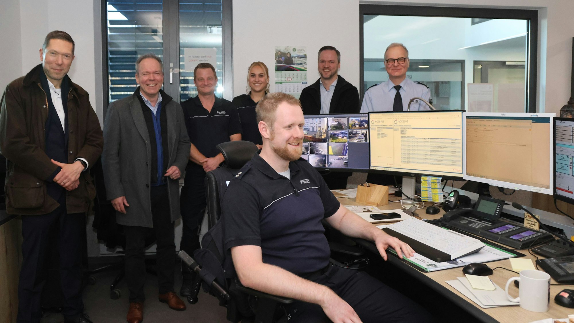 Eine Gruppe im Hintergrund, vorn ein Mann am Computerterminal.