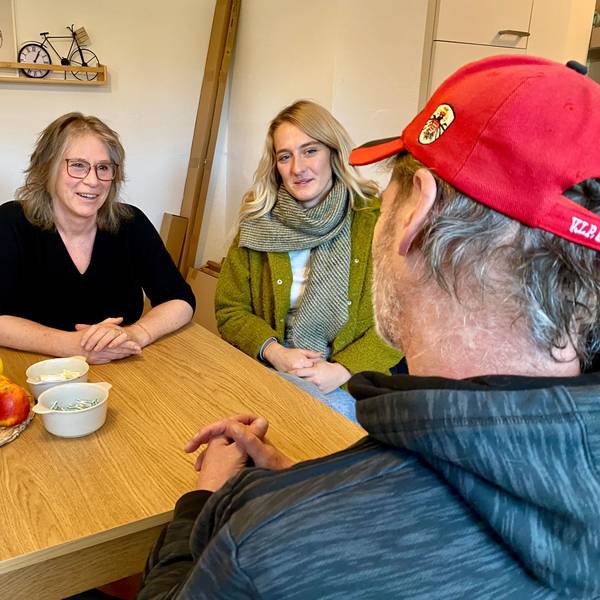 Maria Surges-Brilon und Gina Raths sitzen am Tisch und sind im Gespräch mit dem Bewohner, den man nur von hinten sieht.