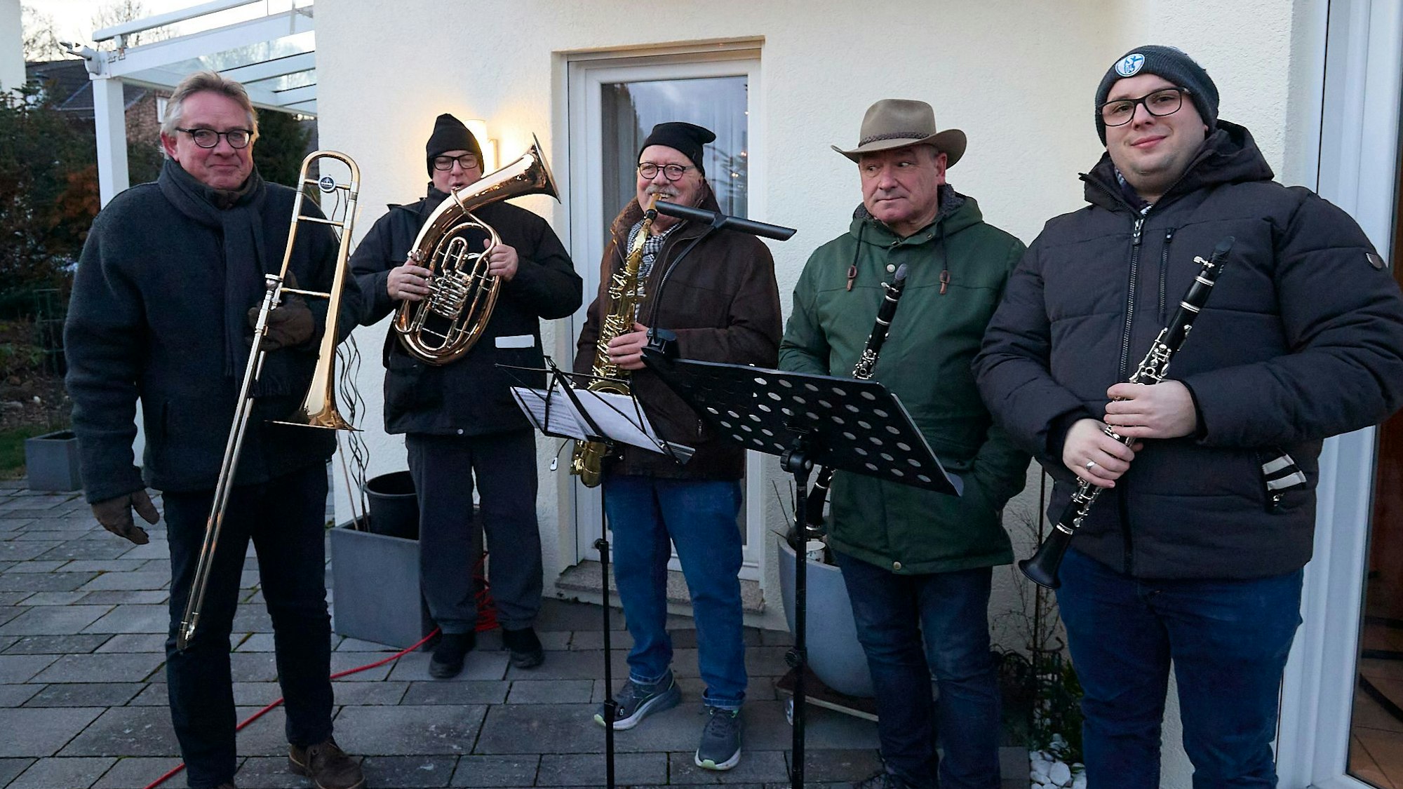 Dick eingemummelt in Winterjacken stehen die fünf Mitglieder der Kapelle nebeneinander. In den Händen halten sie ihre Blasinstrumente.