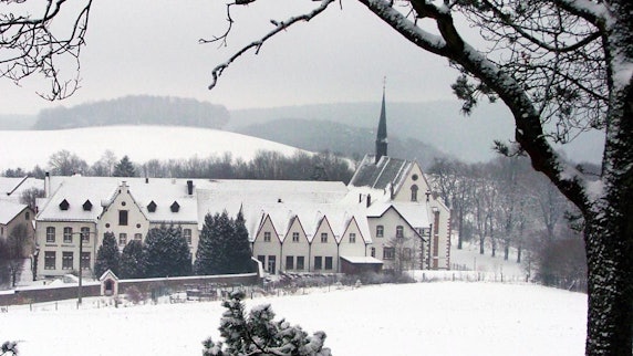 In der verschneiten Winterlandschaft sieht man die Gebäude von Kloster Mariawald.
