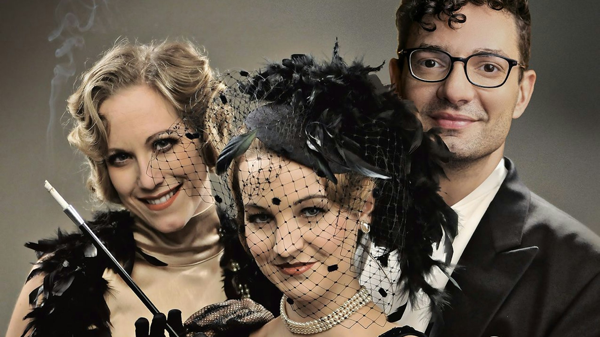 Zwei Frauen und ein Mann in 20er-Jahre-Kostümen lächeln.