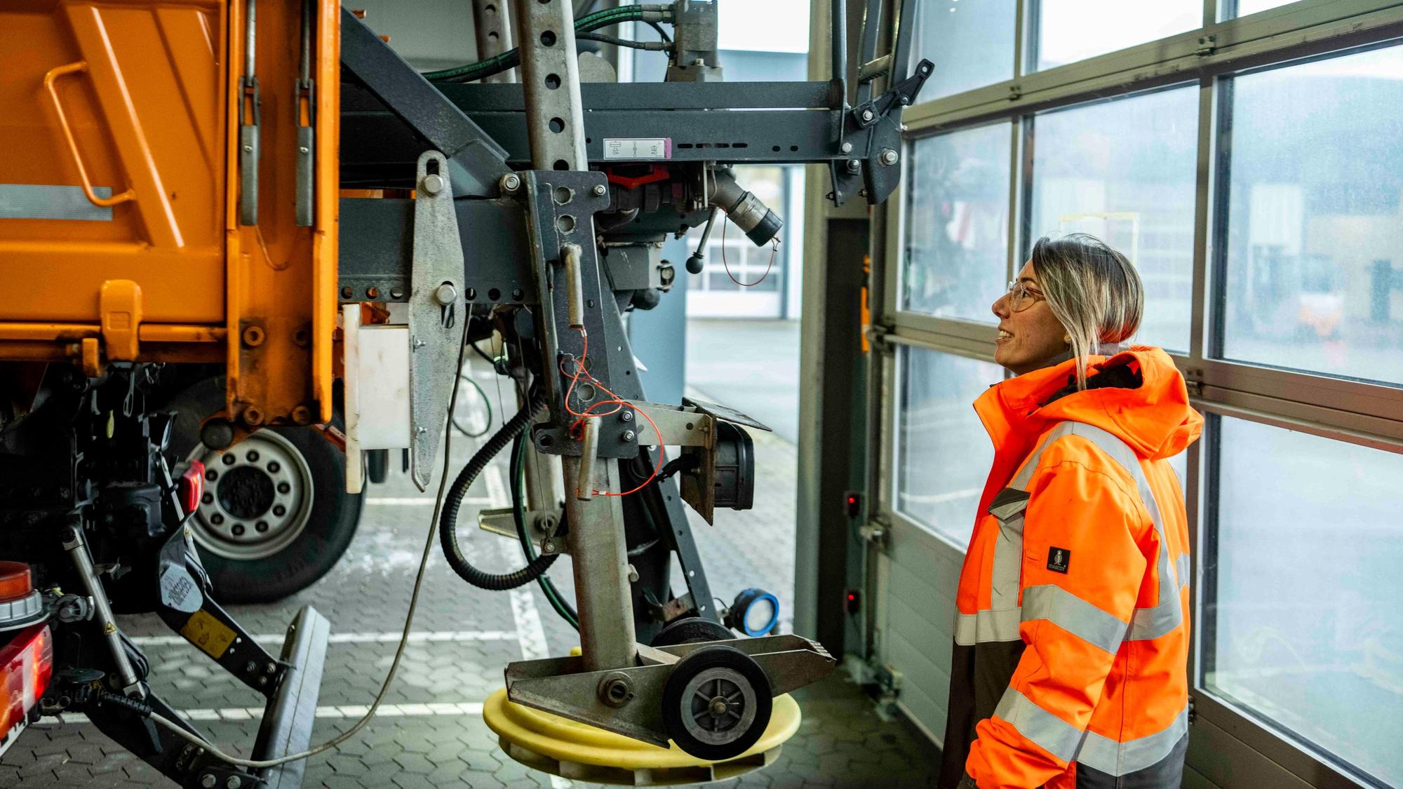 Eva Heinen mustert die Technik des Salzstreuers am Räumfahrzeug.