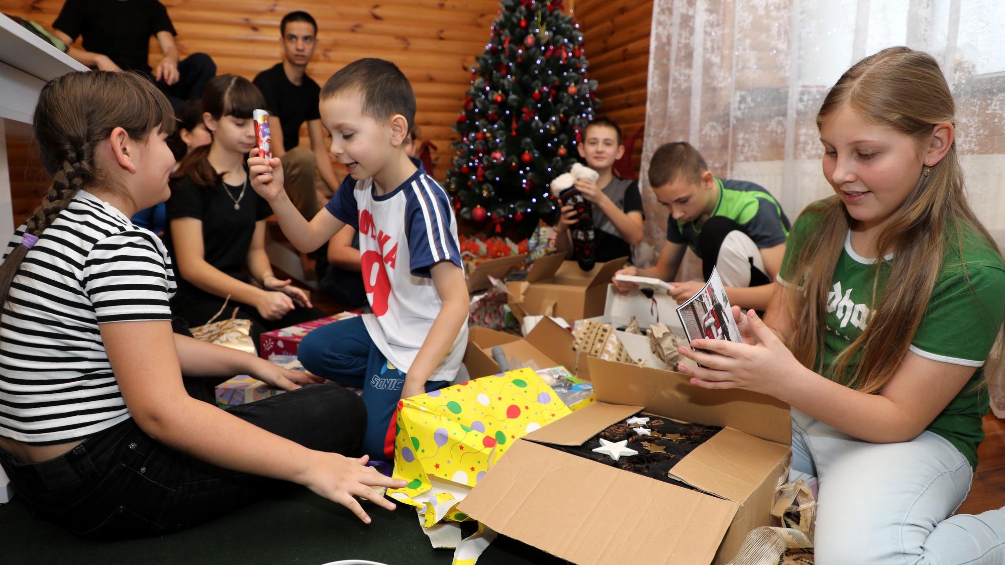 Kinder in einem Kinderhaus in Butscha packen die Geschenke unterm Weihnachtsbaum aus.