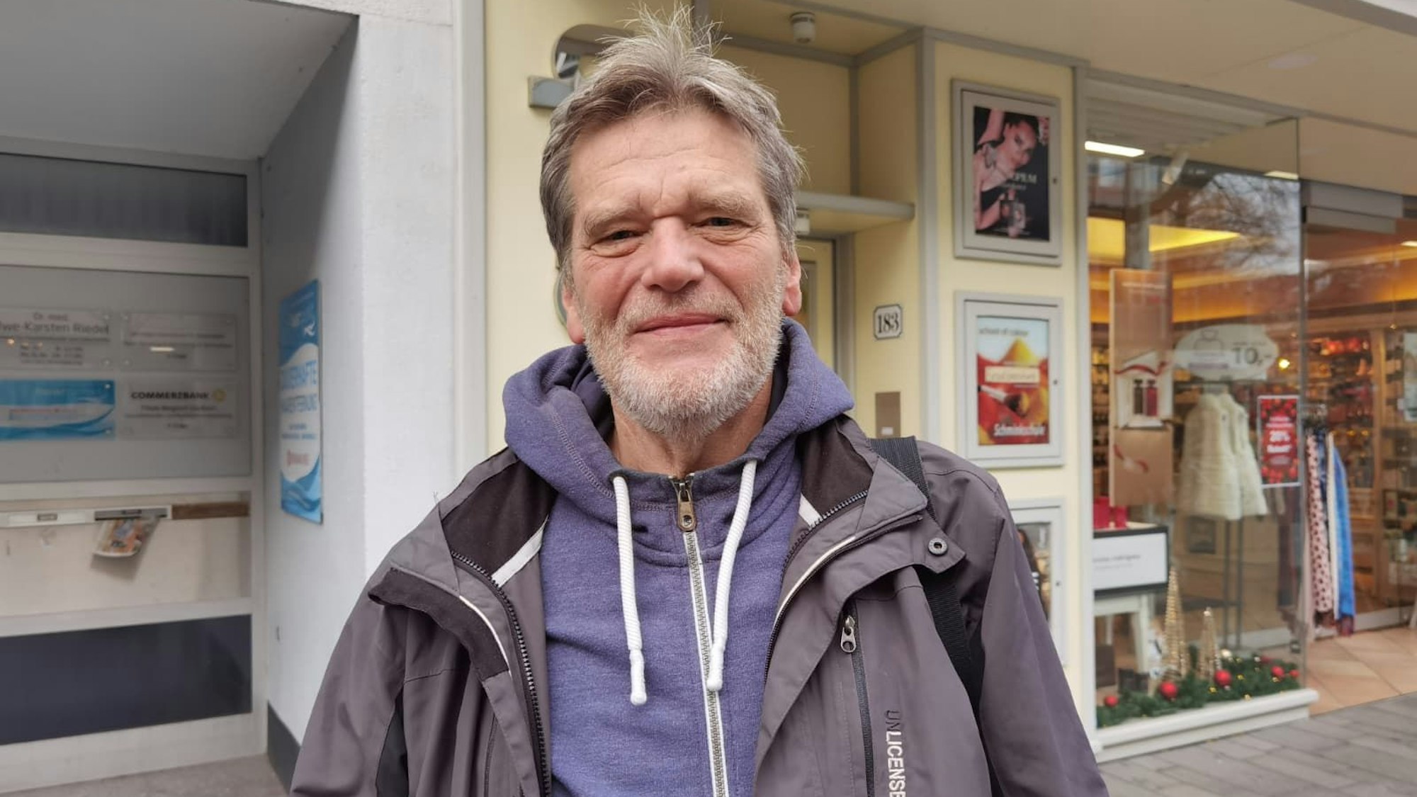 Ein Mann mit einer Jacke an lächelt in die Kamera.