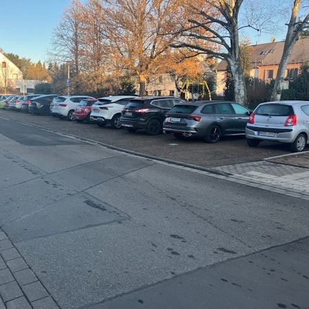 Eine Straße, an der rechten Seite parken Autos.